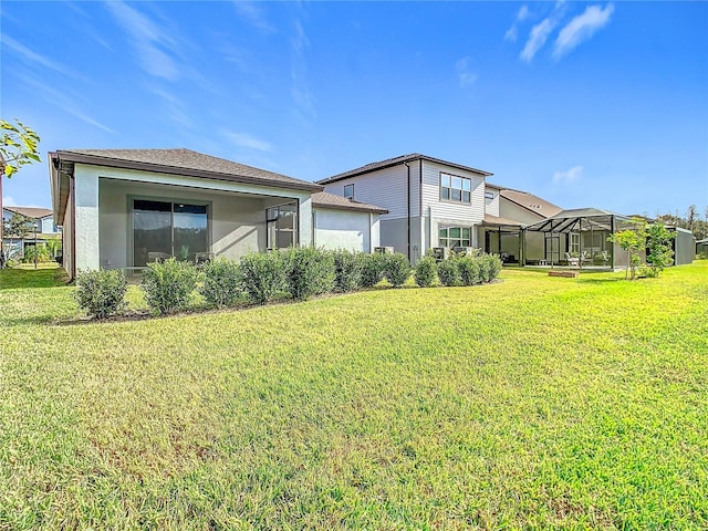 rear view of property with glass enclosure and a yard