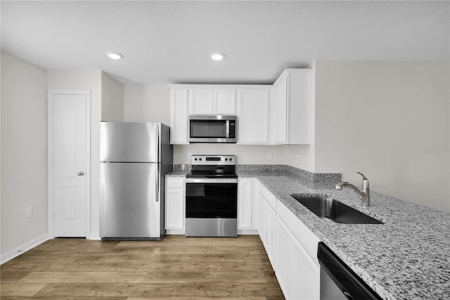 kitchen featuring light stone countertops, sink, appliances with stainless steel finishes, white cabinets, and light wood-type flooring