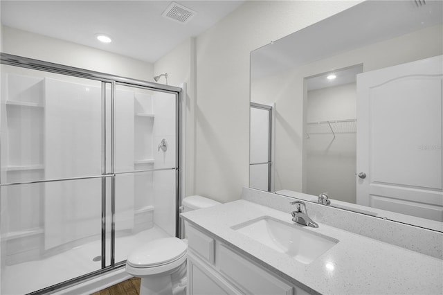 bathroom featuring hardwood / wood-style floors, vanity, toilet, and a shower with shower door