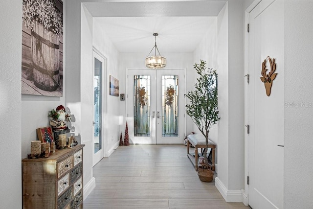 entrance foyer with french doors, a notable chandelier, and wood-type flooring