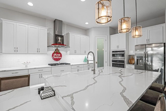 kitchen with light stone countertops, pendant lighting, wall chimney exhaust hood, white cabinetry, and a breakfast bar area