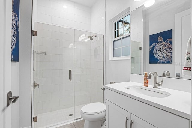 bathroom with toilet, a shower with shower door, and vanity