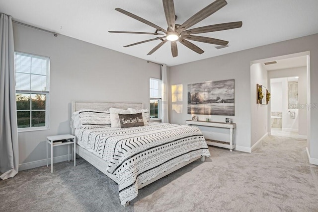 carpeted bedroom with ensuite bath, ceiling fan, and multiple windows