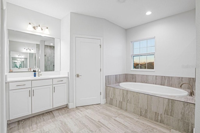 bathroom featuring vanity and tiled tub