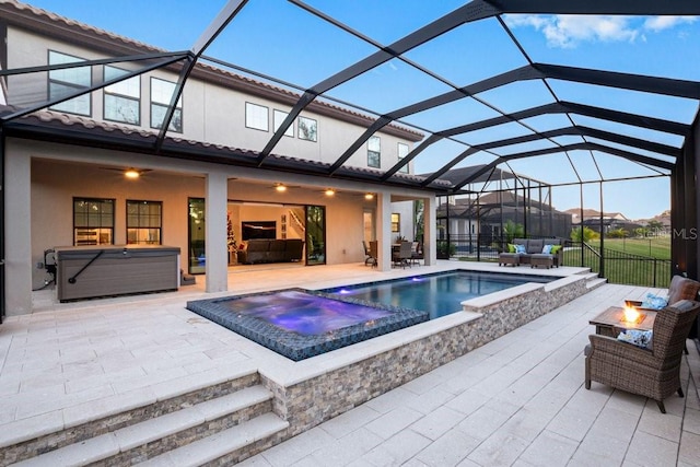 view of swimming pool featuring a lanai, a patio area, an outdoor living space with a fire pit, and an outdoor hot tub