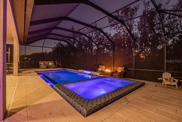 pool at dusk featuring an in ground hot tub, a patio area, and a lanai