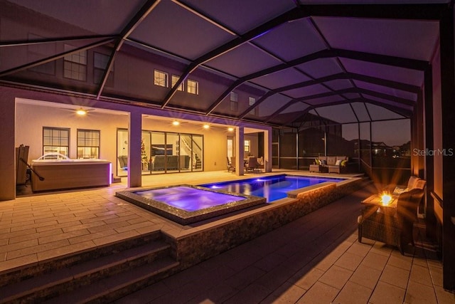 view of pool with a patio, glass enclosure, and an in ground hot tub