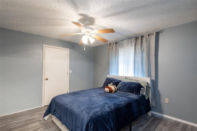 bedroom with dark hardwood / wood-style floors, ceiling fan, and a textured ceiling