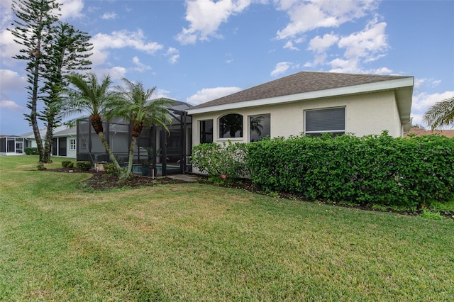 view of front of home featuring glass enclosure and a front lawn