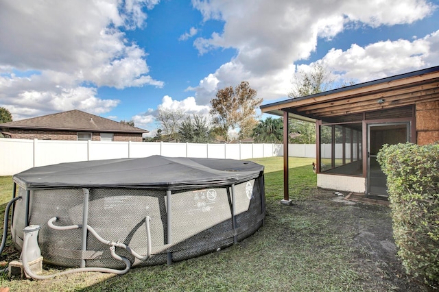 view of yard with a sunroom and a covered pool