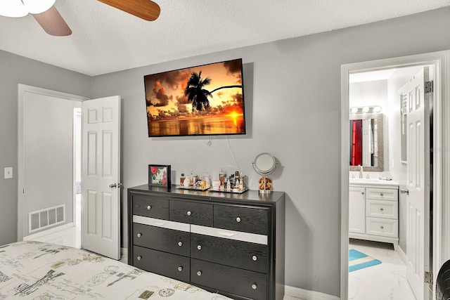 bedroom with a textured ceiling, ensuite bath, ceiling fan, and sink