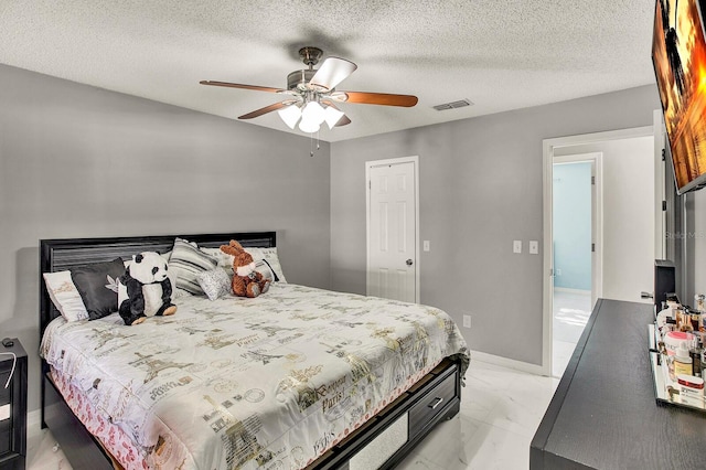 bedroom with ceiling fan and a textured ceiling