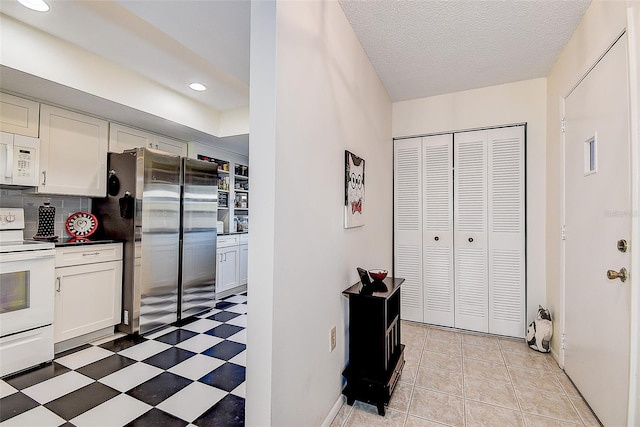 kitchen with a textured ceiling, white appliances, tasteful backsplash, and white cabinetry