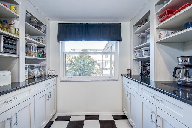 kitchen featuring white cabinetry and dark stone counters