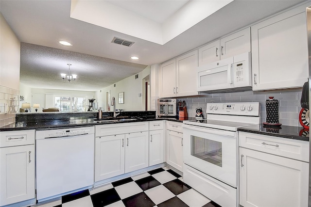 kitchen with white appliances, white cabinetry, and a notable chandelier