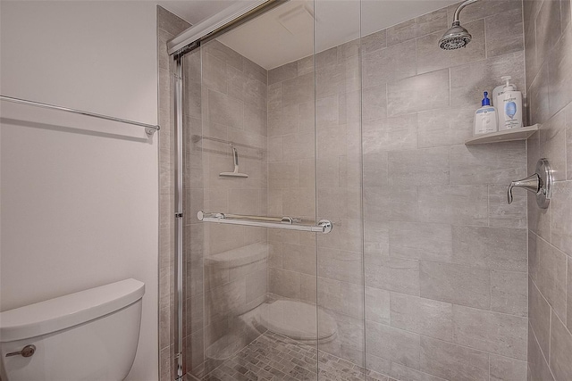 bathroom featuring toilet and a shower with door