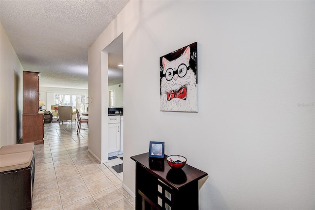 hallway featuring light tile patterned floors and a textured ceiling