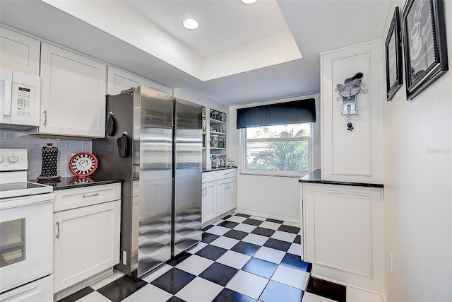 kitchen featuring white cabinets, white appliances, a raised ceiling, and backsplash