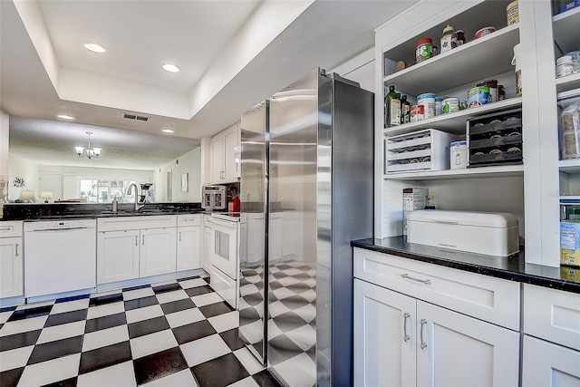 kitchen with stainless steel fridge, white cabinets, sink, dishwasher, and a chandelier