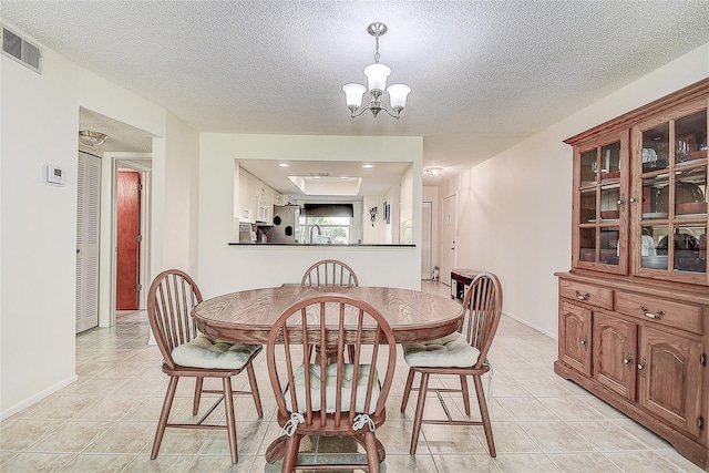 tiled dining space with sink, a textured ceiling, and a notable chandelier