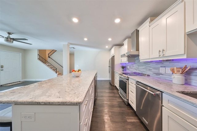 kitchen with a center island, white cabinets, stainless steel appliances, and wall chimney range hood