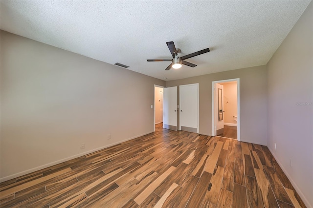 unfurnished bedroom featuring ceiling fan, dark hardwood / wood-style flooring, a textured ceiling, and connected bathroom