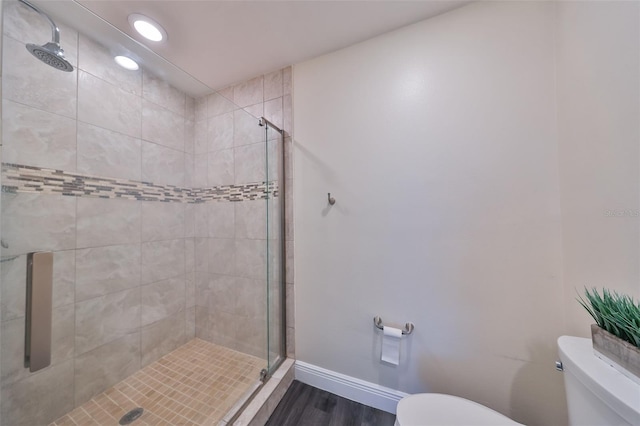 bathroom featuring hardwood / wood-style floors, a shower with shower door, and toilet