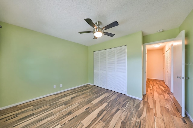 unfurnished bedroom with a textured ceiling, a closet, hardwood / wood-style flooring, and ceiling fan