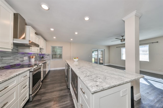 kitchen with white cabinetry, dark wood-type flooring, stainless steel appliances, light stone counters, and a kitchen island