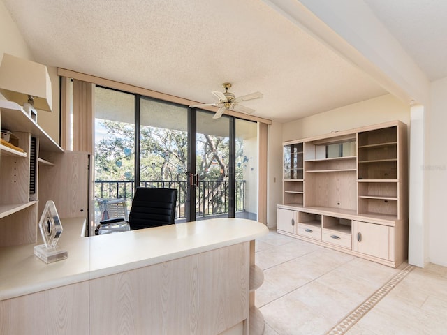 unfurnished office with a wealth of natural light, ceiling fan, a textured ceiling, and a wall of windows