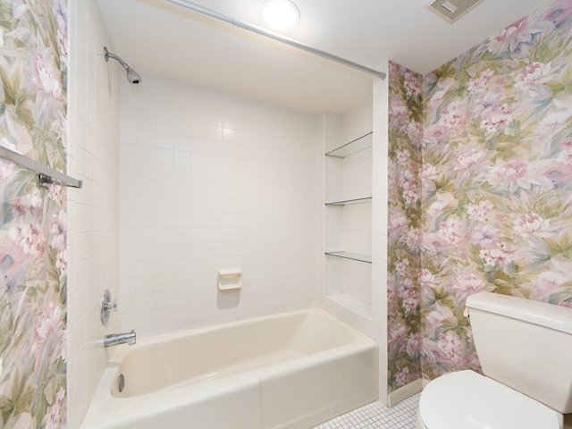 bathroom with tile patterned floors, tiled shower / bath combo, and toilet