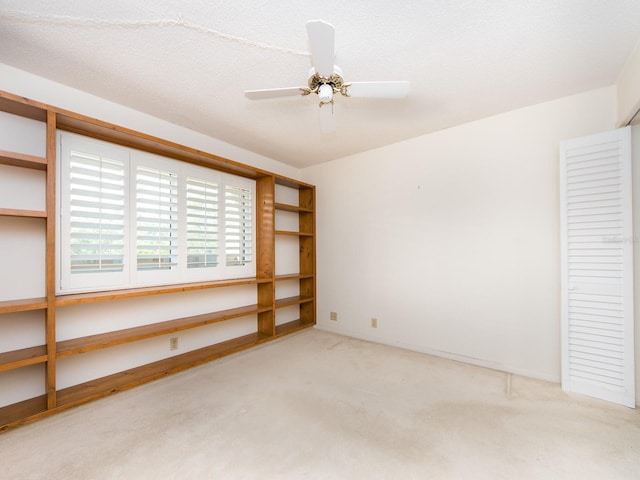 empty room featuring ceiling fan and light carpet