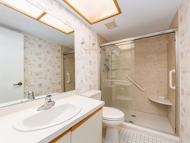 bathroom featuring tile patterned flooring, vanity, toilet, and a shower with door