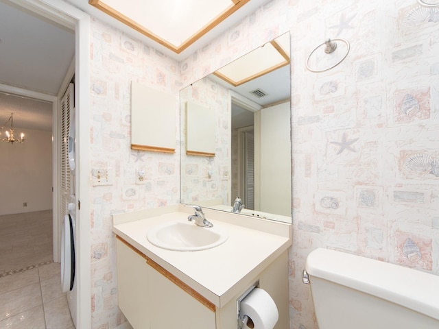 bathroom featuring tile patterned flooring, vanity, toilet, and an inviting chandelier