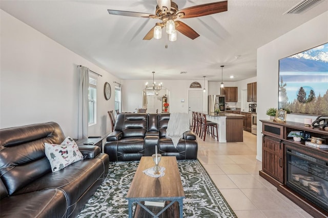 living room with ceiling fan with notable chandelier and light tile patterned floors