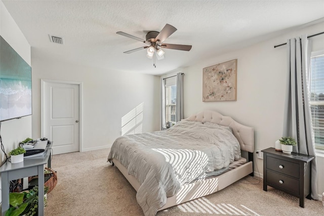 carpeted bedroom featuring ceiling fan and a textured ceiling