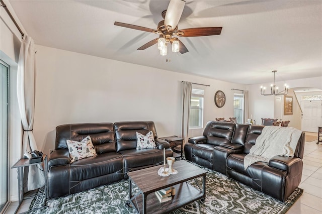 tiled living room with ceiling fan with notable chandelier