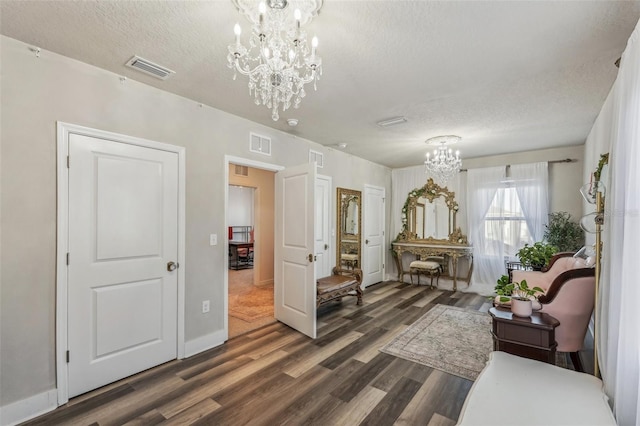 living area with a chandelier, a textured ceiling, and dark hardwood / wood-style flooring