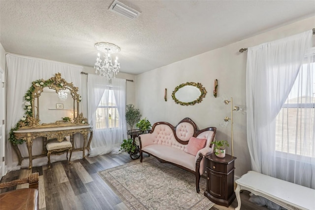 living area featuring hardwood / wood-style floors, a textured ceiling, and a notable chandelier