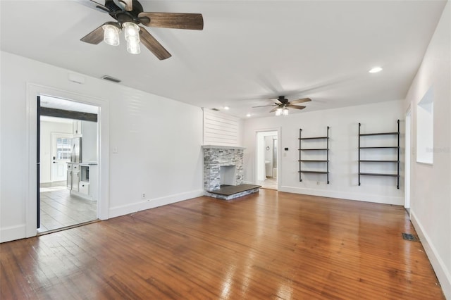 unfurnished living room with ceiling fan, wood-type flooring, and a fireplace