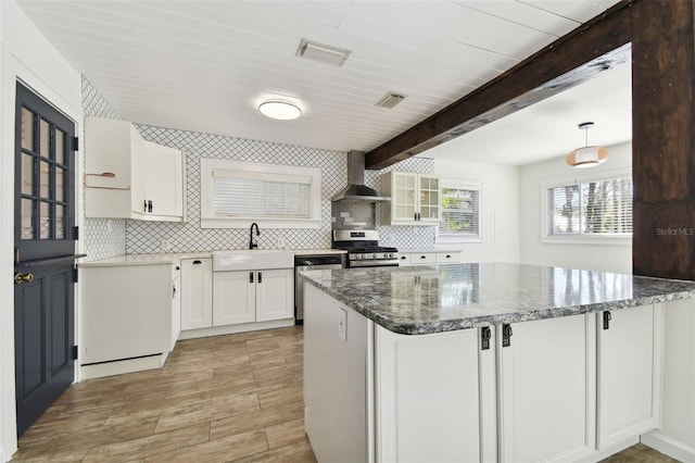 kitchen with white cabinets, decorative backsplash, wall chimney range hood, and appliances with stainless steel finishes