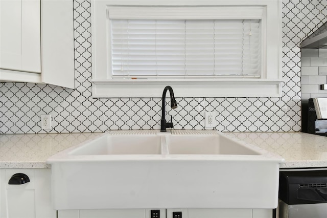 kitchen with white cabinets, backsplash, light stone counters, and sink