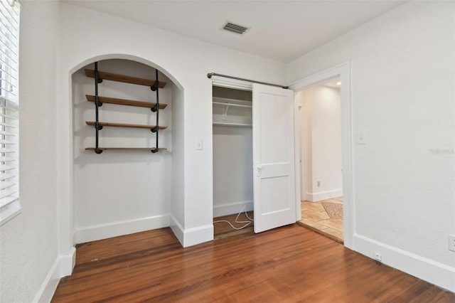 unfurnished bedroom featuring wood-type flooring and a closet