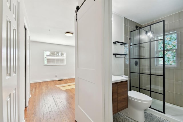 bathroom with a tile shower, hardwood / wood-style floors, vanity, and toilet