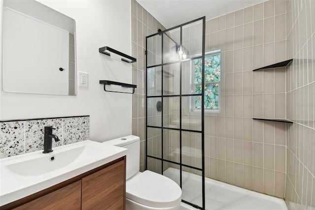 bathroom with vanity, toilet, and a tile shower