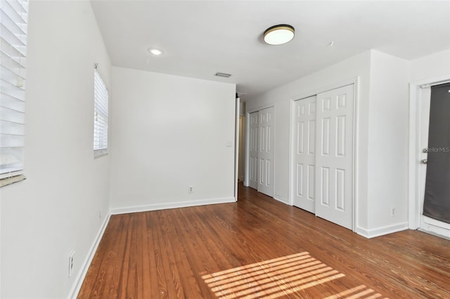 unfurnished bedroom with wood-type flooring and two closets