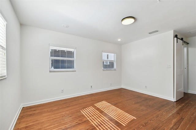 spare room with a barn door and dark hardwood / wood-style flooring