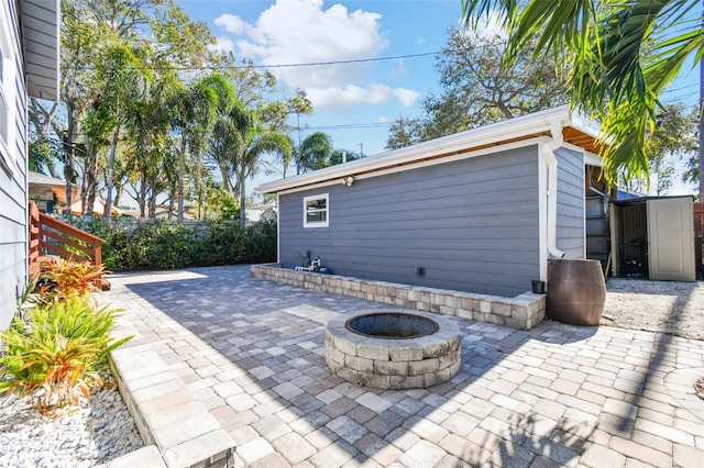 view of patio / terrace featuring an outdoor fire pit and a storage shed