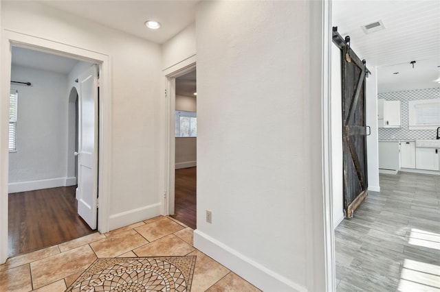 corridor with a barn door and light wood-type flooring