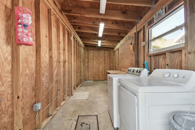 laundry area with separate washer and dryer and wooden walls